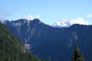 Near the top of ridgeline, Glacier Peak rises above the opposite mountains.