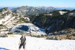 Brian on the snow above Upper Robin Lake, Glacier Peak distant