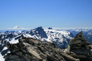 Cairn on top of Mt. Hinman, Summit Chief and Mt. Rainier visible...